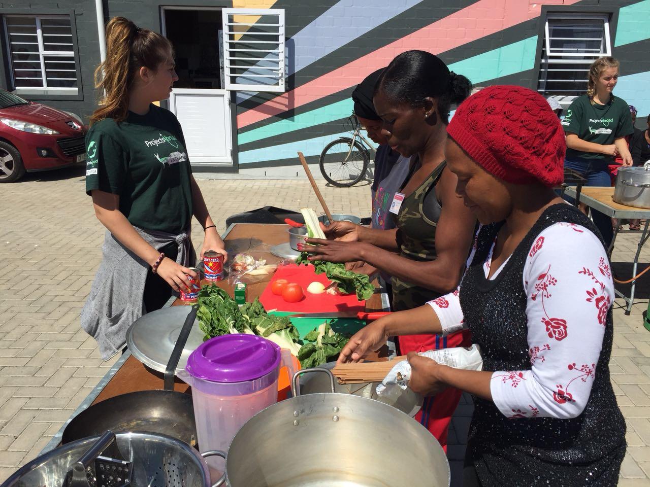A group of South African women are pictured cooking healthy meals during a cooking competition, taken by a Projects Abroad intern whilst on her nutritional internship in South Africa. An intern on a nutritional internship in South Africa pictures a trio of women cooking healthy meals as part of a cooking competition.